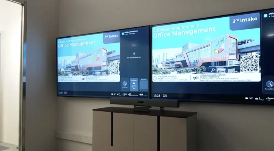 Neat Bar Pro mounted under dual wall displays showing an Offision Office Management programme.